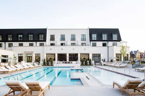 Modern white resort with lap pool, lounge chairs, and manicured grounds