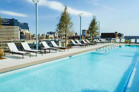 Modern rooftop pool with lap lanes, lounge chairs, and city skyline views