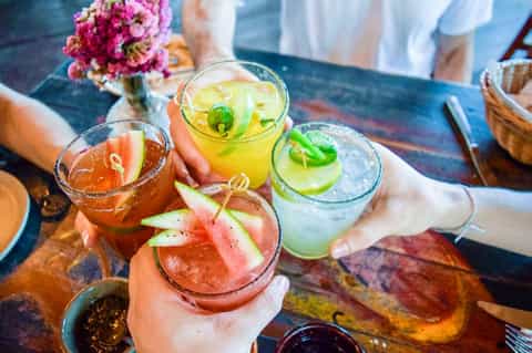 Colorful cocktails garnished with fresh fruit and herbs served at an outdoor dining table