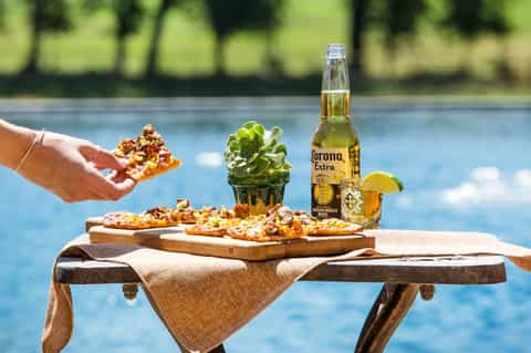 Poolside table with Corona beer, appetizers, small cactus plant, and scenic river backdrop