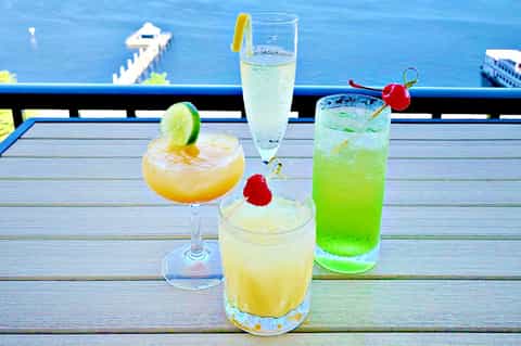 Tropical cocktails with garnishes on a dock overlooking blue ocean water