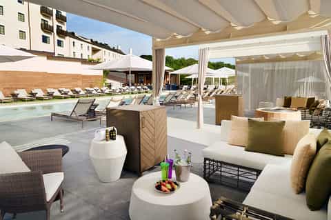 Resort pool deck with lounge chairs, white pergolas, and modern lounge seating area