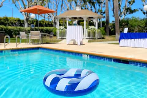 Resort pool with blue and white striped float, umbrellas, and gazebo