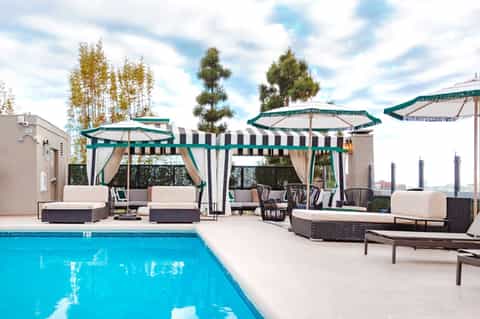 Resort poolside with teal umbrellas, lounge chairs, and modern building architecture