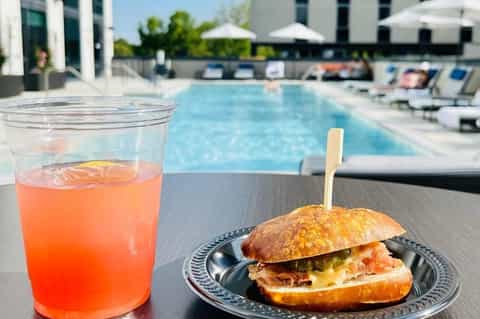 Poolside food and beverage service with cocktail and sandwich near resort swimming pool