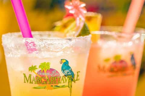 Colorful margarita cocktails with pink straws, salt-rimmed glasses, and tropical garnishes