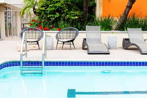 Poolside seating with modern lounge chairs and round accent tables by bright blue pool