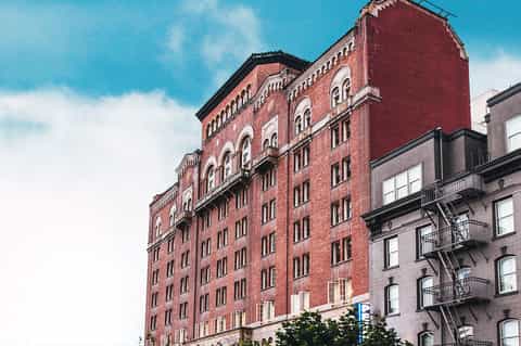 Historic red brick building with arched windows and fire escapes in urban setting