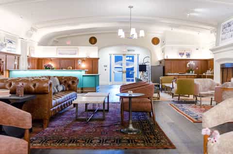 Upscale hotel lobby with leather seating, wooden reception desk, decorative rugs, and arched ceiling