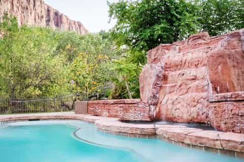 Turquoise pool nestled among red rock formations and desert vegetation