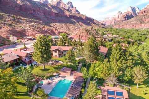 Aerial view of mountain resort nestled in red rock canyon landscape with pool and manicured grounds