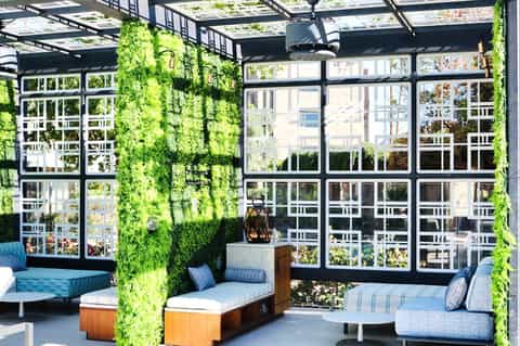 Modern rooftop lounge with living green walls, black pergola, and contemporary seating areas