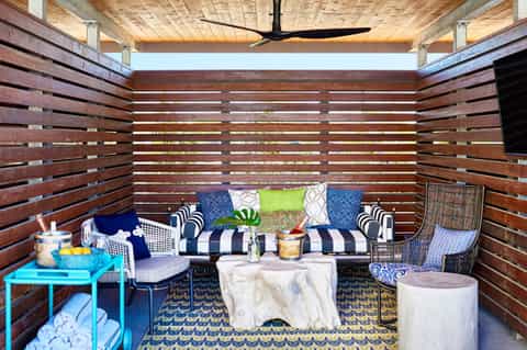 Modern wooden lounge with navy striped seating, colorful pillows, and geometric rug