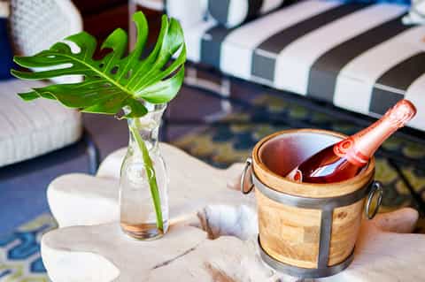 Spa treatment setup with green monstera plant, wooden mortar and pestle, striped lounge chair
