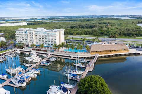 Waterfront hotel with blue building, marina with boats, and lush greenery
