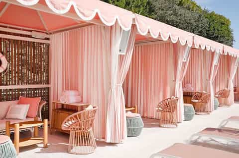 Pink and white draped cabanas with lounge chairs on a luxury resort deck