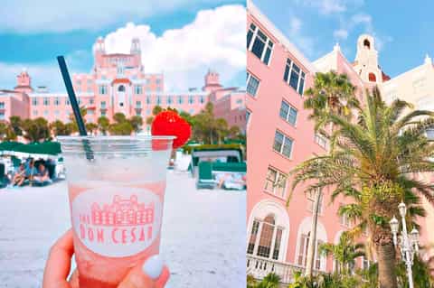 Pink cocktail with cherry garnish held in front of pastel pink hotel buildings and beach