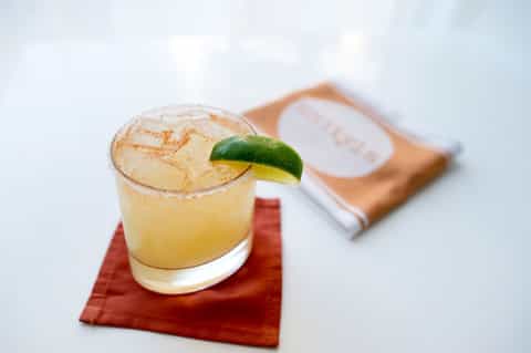 Margarita cocktail with lime garnish and salt rim on red napkin