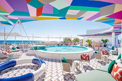 Vibrant rooftop pool area with colorful geometric canopy and lounge seating