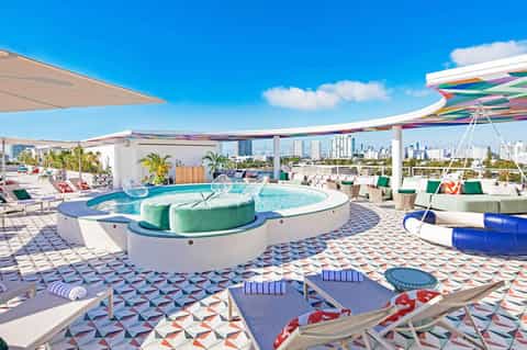 Rooftop pool deck with colorful umbrellas, modern seating, and city skyline views