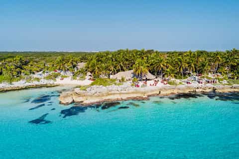 Aerial view of tropical beach resort with turquoise water, palm trees, and sandy coastline