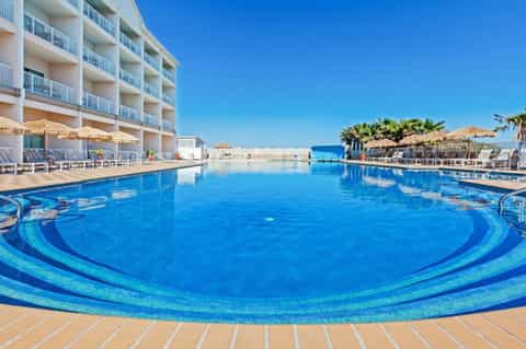 Resort pool with decorative beach balls and white lounge chairs along the waterfront