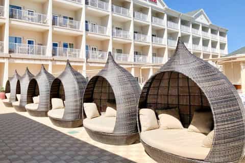 Resort deck with wicker pod loungers and multi-story hotel building backdrop