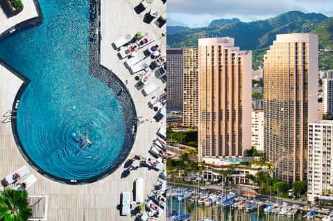 Aerial view of circular pool deck with lounge chairs and high-rise hotel towers overlooking mountains and marina