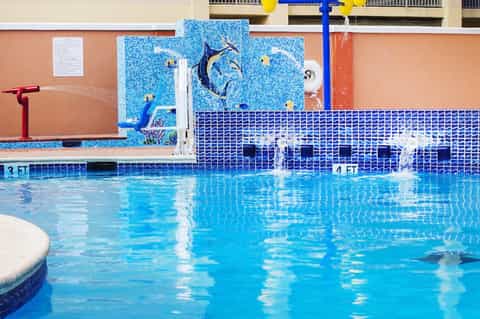 Olympic-style competition swimming pool with diving board and decorative tile artwork
