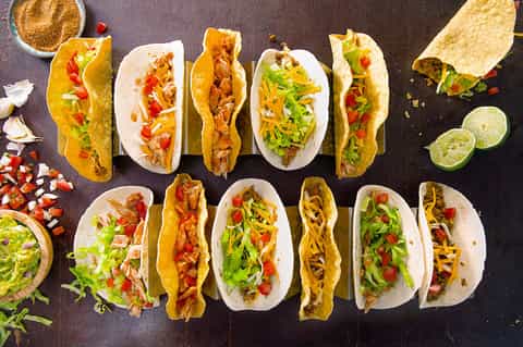 Assorted tacos with various fillings, lime wedges, and condiments