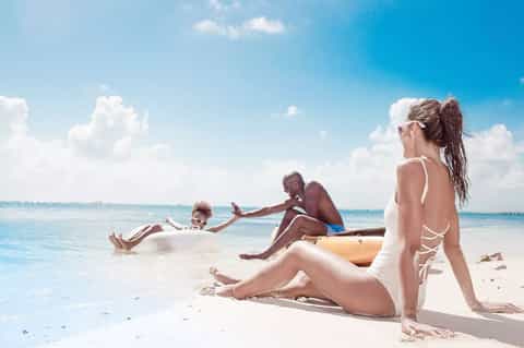 Family enjoying beach with turquoise water, white sand, and clear blue sky