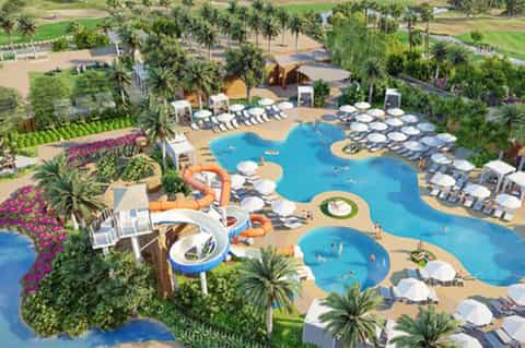 Aerial view of resort pool complex with water slides, loungers, and lush landscaping
