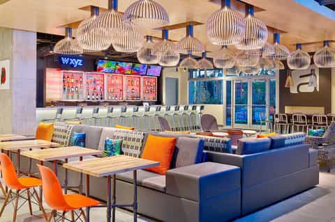 Modern hotel lounge with bar, colorful pendant lights, and contemporary seating