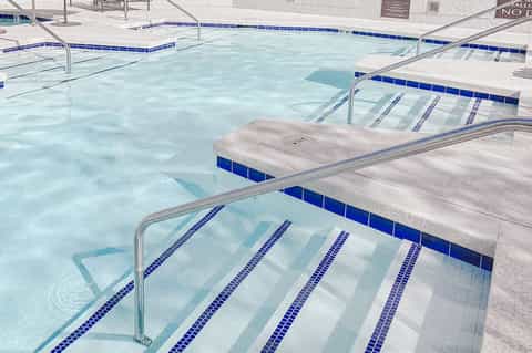Indoor lap pool with lane dividers and white towels on deck chairs
