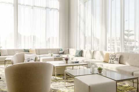 Bright modern lounge with cream sectional sofa, floor-to-ceiling windows, and contemporary furnishings