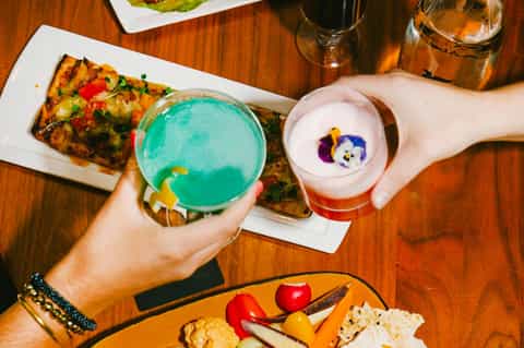 Colorful cocktails and appetizers on wooden table at upscale restaurant or bar