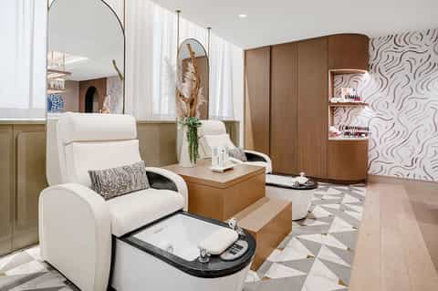 Luxury spa pedicure station with white leather chair, wooden accents, and elegant mirrors