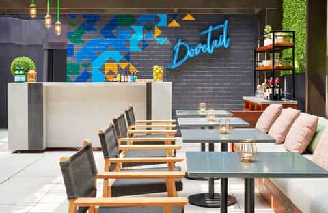 Modern restaurant interior with colorful geometric mural and blue neon 'Dorelah' sign