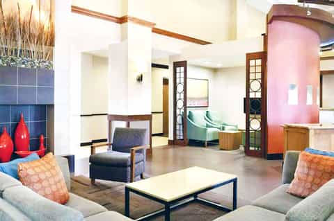 Contemporary hotel lobby with colorful accents, seating areas, and art gallery wall