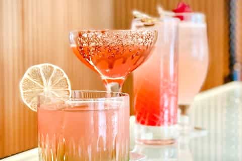 Colorful cocktails with citrus garnishes and sparkling rims displayed on a wooden counter