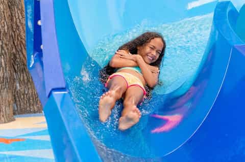Child enjoying a blue water slide at a resort pool