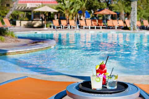 Poolside cocktails with tropical drinks at a resort with blue pool and orange lounge chairs