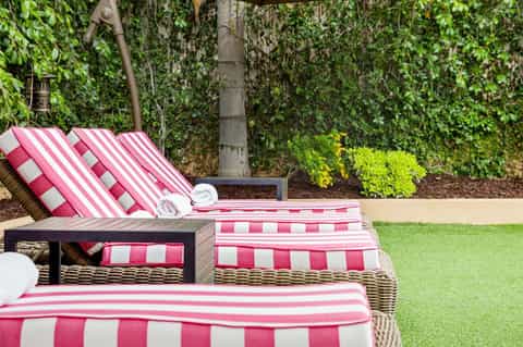 Pink and white striped lounge chairs with cushions in a garden setting