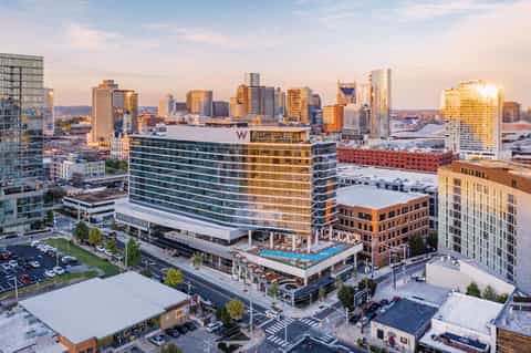 Urban hotel with rooftop pool at sunset, downtown skyline, and surrounding city buildings