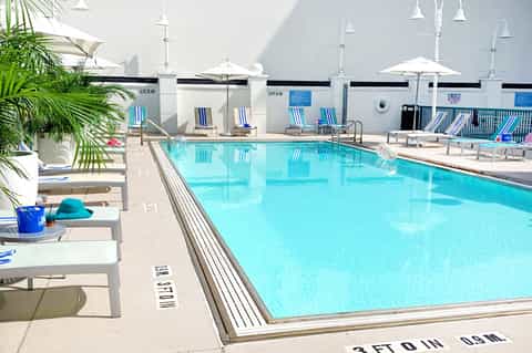 Resort lap pool with blue water, white umbrellas, and lounge chairs on sunny day