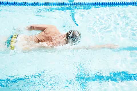 Swimmer doing freestyle stroke in a lap pool with lane dividers during competition