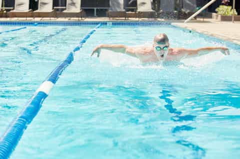 Competitive swimmer doing butterfly stroke in Olympic-style lap pool with lane dividers