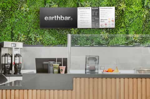Earthbar café counter with green living wall backdrop and menu display