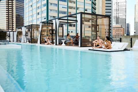 Rooftop pool with modern pergolas, lounge areas, and downtown city skyline