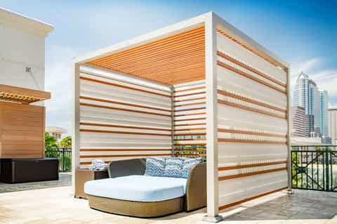 Outdoor daybed with striped canopy on rooftop terrace overlooking city skyline